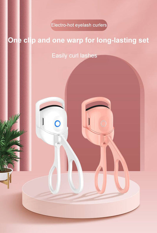 Heated Eyelash Curler in white and pink designs on a round podium with a modern backdrop.